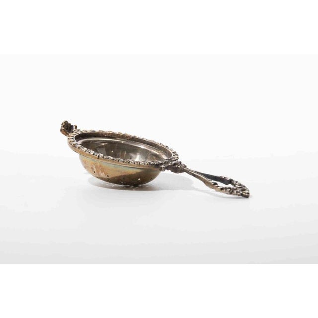 Elegant vintage tea strainer crafted in 800 silver, featuring a pierced bowl, twisted rope-style rim, and ornate...