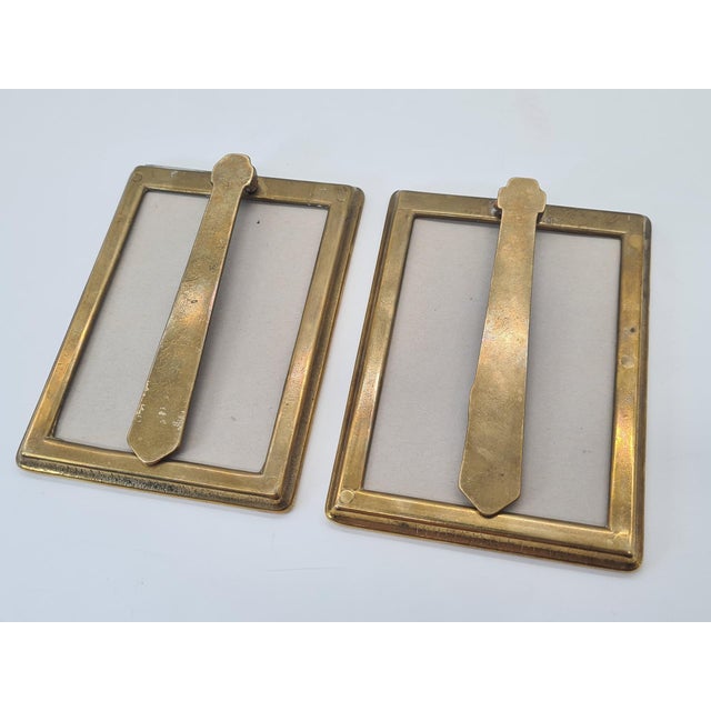 An elegant pair of brass picture frames with a simple, geometric design and a distinctive oval opening for a photograph....