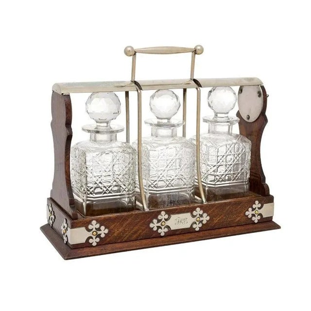 An English Victorian period wooden tantalus from the 19th century, with three cut glass decanters, key locking mechanism...