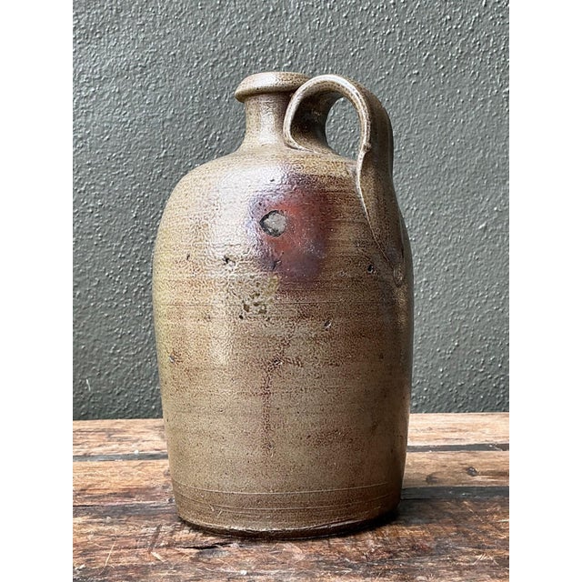 This authentic antique stoneware jug exemplifies the enduring beauty of early utilitarian ceramics, where form and...
