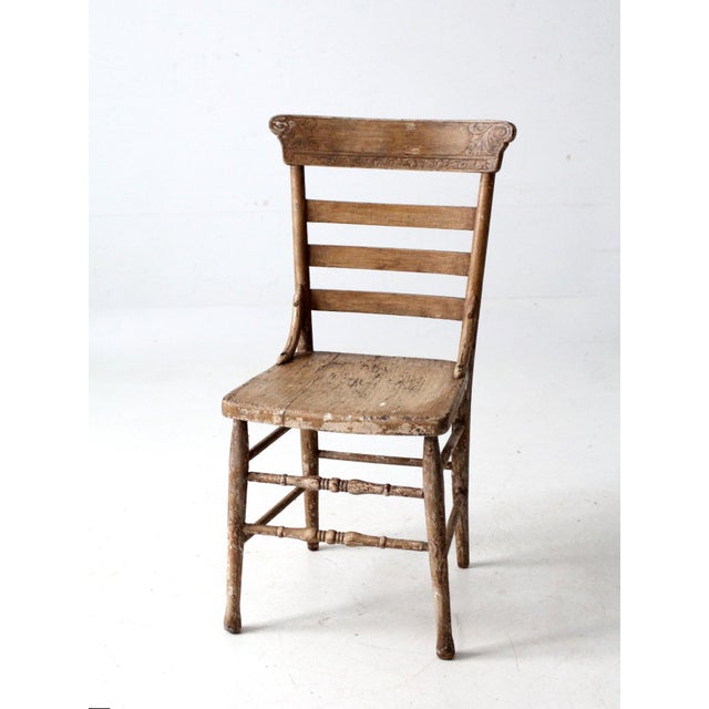 An antique American country chair dating to the late 19th to early 20th century, featuring a shaped ladder back with...