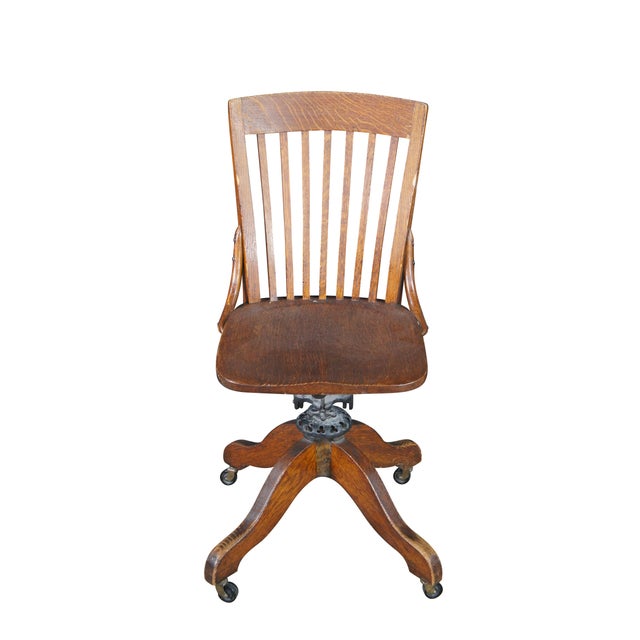 Antique Milwaukee quartersawn oak bankers / lawyers / executive desk chair featuring a slatted back and rolling castors....