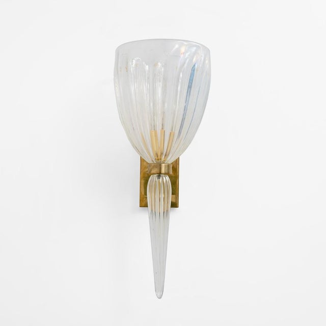 An elegant pair of 1990s italian wall lamps, crafted from fluted, iridescent murano glass with a brass frame. Each lamp...
