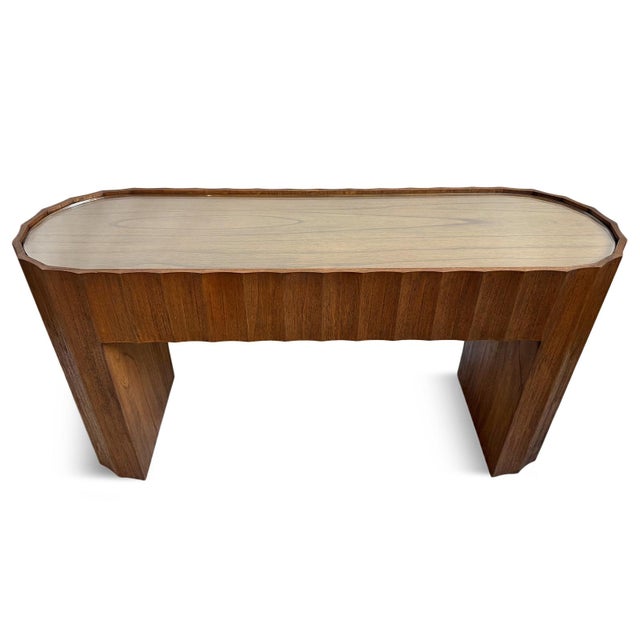 Rich brown Mindi wood console table with smooth scalloped design and oval shape. Removable inset glass top included. Each...
