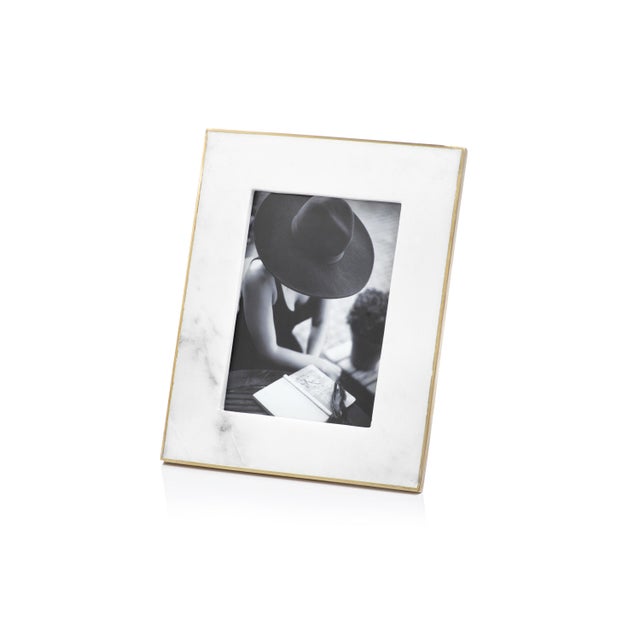 White marble frame features matt gold brass edge and holds 5 inches x 7 inches photo inserted through back of frame....