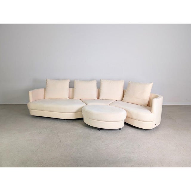 Beautiful three-piece Rolf Benz design corner sofa, including an ottoman. The sofa is upholstered in high-quality light-...
