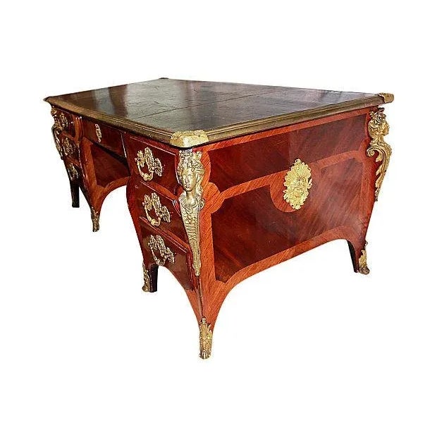 An 1880s faux-partners desk in rosewood, mahogany, doré bronze mounts and gilt tooled leather top. This desk was from...