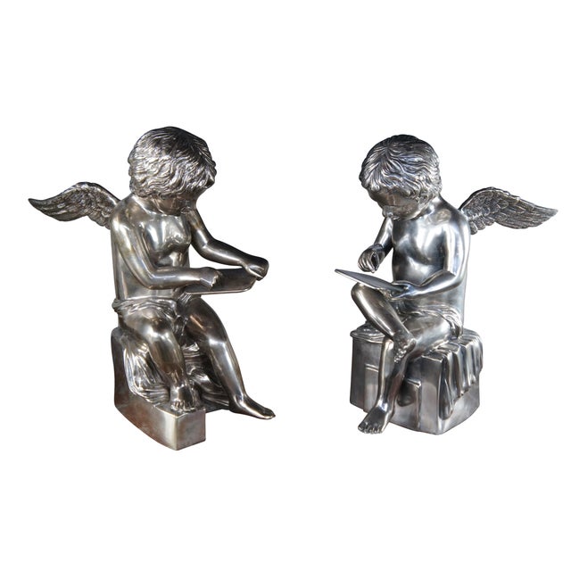 Cover hollowware sculptural angel figurines or bookends. Each boy is seated on a plinth with a tablet in hand and...