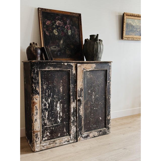 A substantial English pine cupboard with a richly layered, chippy black painted finish worn back to reveal warm undertones...