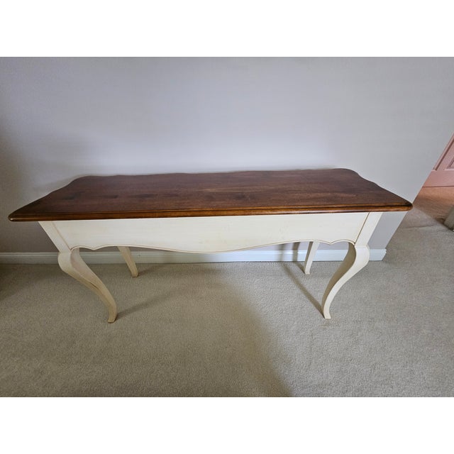 A lovely Country French sofa table with three drawers, some distressing, and a two-toned finish. Would look great in a...