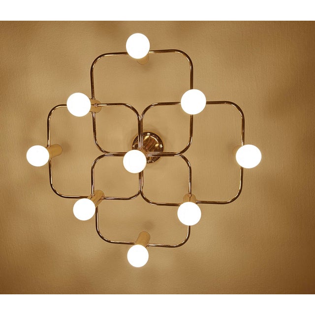 Architectonic flush light featuring a four leaves clover shaped arrangement of 9 intertwined spokes , all gilded brass...