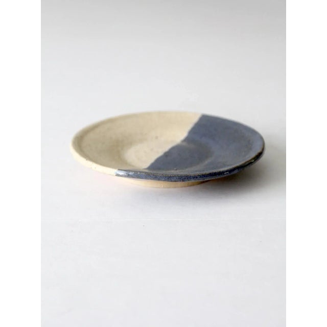 his is a vintage studio pottery plate. Signed by the artist, the handmade plate features a two tone glaze of cream and...