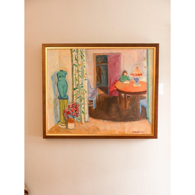 Oil interior of a woman writing at a round table by a lamp, seen past a green torso sculpture on a pedestal, a vase of red...