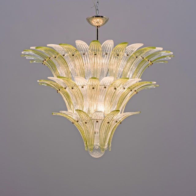 This elegant murano glass chandelier features multiple tiers of palm-shaped glass elements, arranged in a cascading...