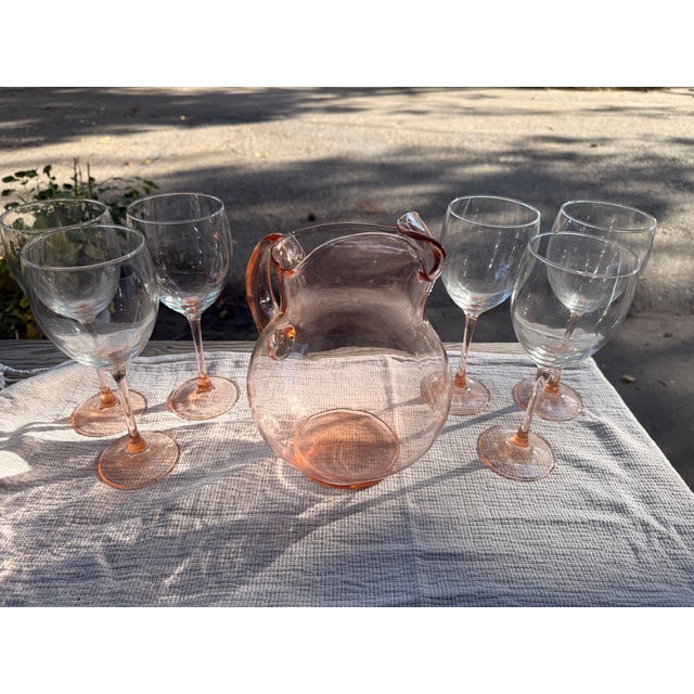 Pink Glass Pitcher and 6 Pink Stemmed Wine Glasses. The stem portion on the glasses is pink while the cup part remains...