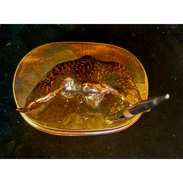 This elegant desk accessory features a detailed bronze-toned ceramic eagle figurine perched on a stand. It serves as a...