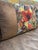At the center of this lumbar cover sits a woven jacquard panel packed with tropical birds in full motion: a large red...