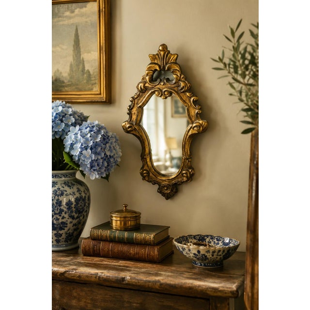 An Italian Rococo–style giltwood wall mirror, richly carved with scrolling acanthus and shell motifs that give the piece...