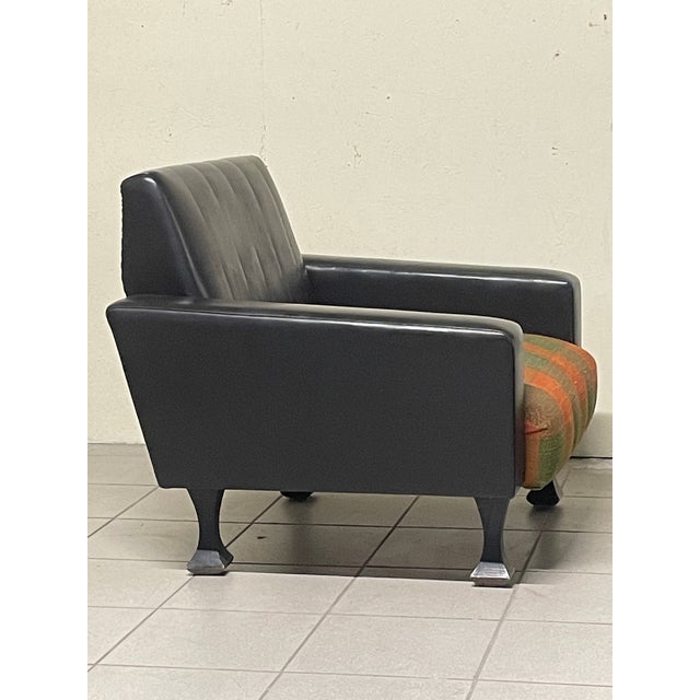 A pair of 1950s Italian-made armchairs with the sleek, square lines typical of the period, featuring a wraparound backrest...