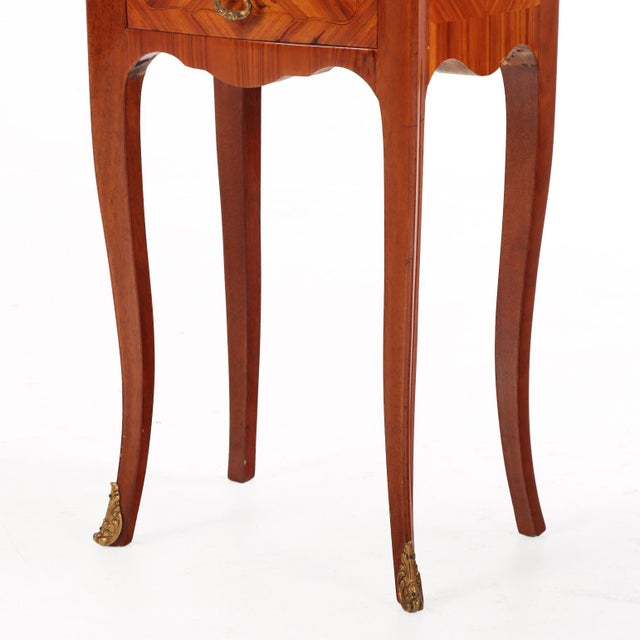 Finely crafted with richly figured wood inlaid surmounted by shaped marble tops, each cabinet is enhanced with finely cast...