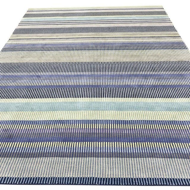 This hand knotted pile rug is crafted from wool and features a primary blue color palette. Defined by a contemporary...