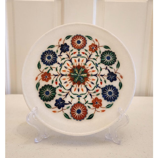 A Pietra Dura white marble decorative plate with inlaid semi-precious stones. Skillfully handcrafted in a floral motif....
