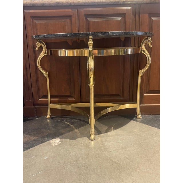 Elevate your space with this stunning Hollywood Regency 1970s Brass Horse Half Circle Console Table with Marble Top,...