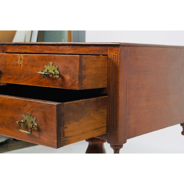 A charming antique mahogany work table with two drawers, decorative brass bail pulls, and an unusually expressive pedestal...