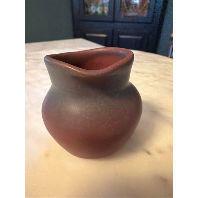 This Vintage Van Briggle Pottery Mulberry Persian 2.5" Pitcher is a handmade clay pitcher in a distinctive round shape,...