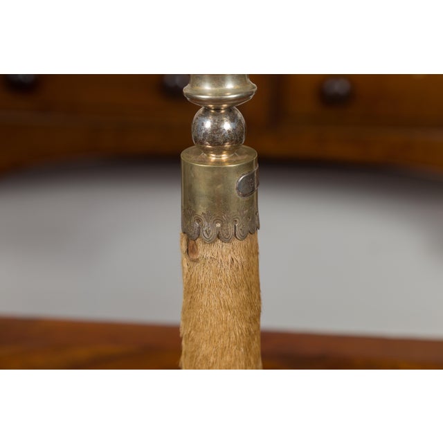 An English deer leg table lamp from the early 20th century, mounted on a circular wooden base. Created in England and...