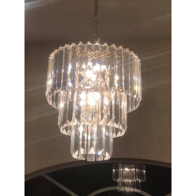 Fabulous set of Mid-Century chandeliers. with clear lucite prisms. The larger chandelier is three tiers and 10 lights. The...