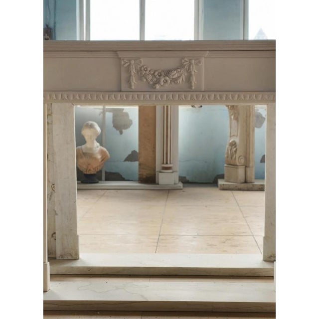 This finely carved neoclassical marble fireplace mantle embodies the grace and symmetry of 18th-century design. The frieze...