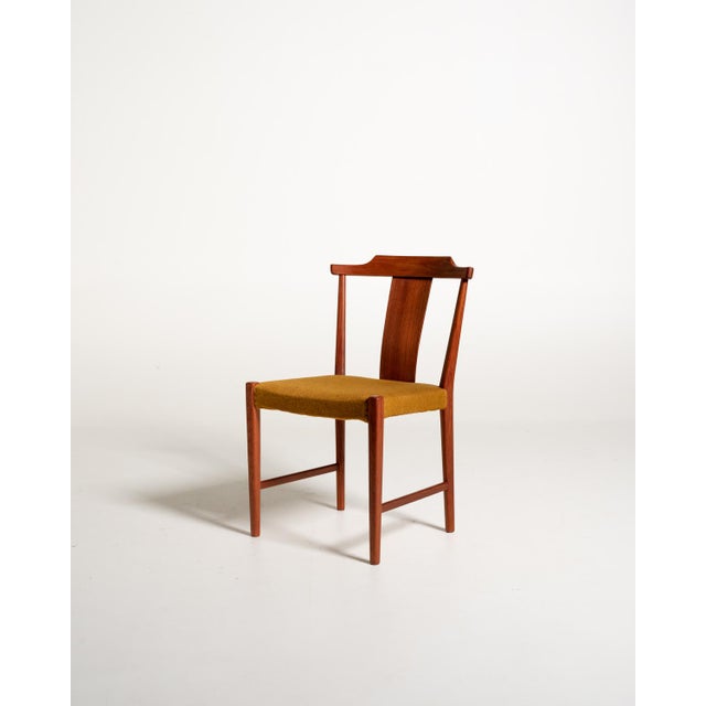 Set of four teak chairs with contoured backrests, ochre-colored fabric-upholstered seats, and tapered legs. Designed by...
