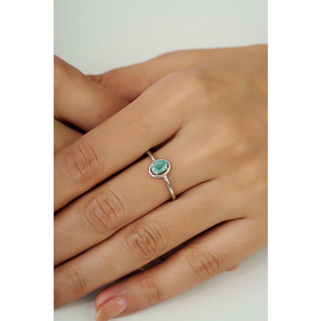 This elegant solitaire ring features a 0.56-carat natural emerald in an oval cut measuring 4 x 6 mm, set in 925 sterling...