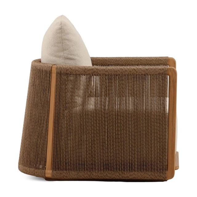Outdoor teak wood frame accent chair with brown poly rope wrap. Cozy sand colored upholstered cushions. Each may vary in...