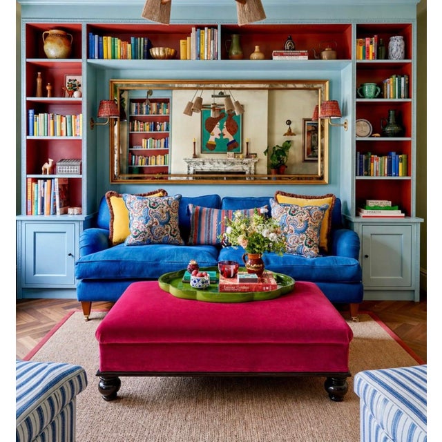 A bold, generously scaled cocktail ottoman upholstered in vibrant fuchsia pink velvet, set on a dark stained wood plinth...