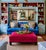 A bold, generously scaled cocktail ottoman upholstered in vibrant fuchsia pink velvet, set on a dark stained wood plinth...