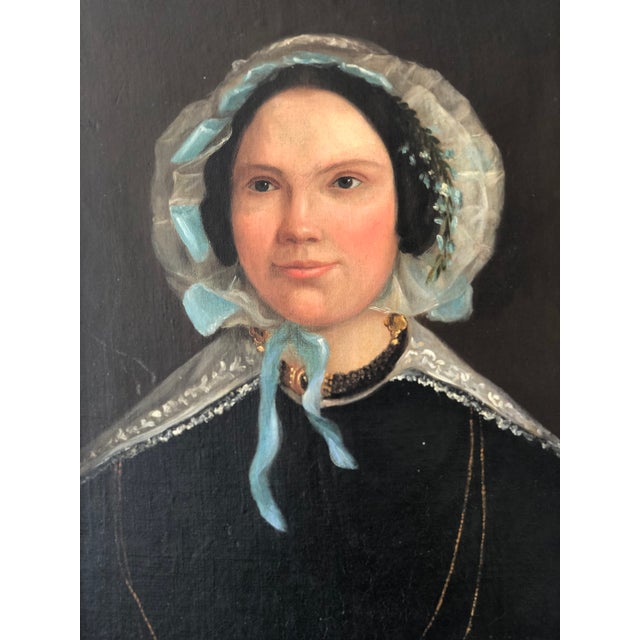 This antique oil portrait painting from the 19th century shows a Dutch lady formally dressed. She wears a black gown with...