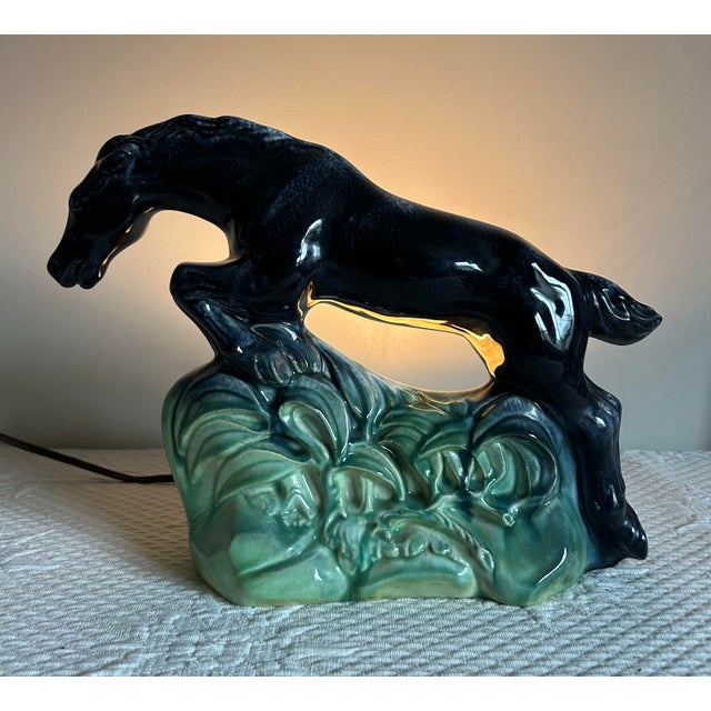 Vintage art deco ceramic television / table lamp made by Haeger. Features a black horse jumping over greenery.