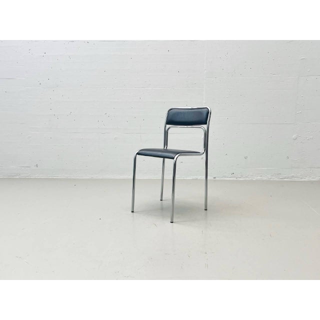 A continuous, curved, high-gloss chrome-plated tubular steel frame forms the seat and backrest, featuring the...