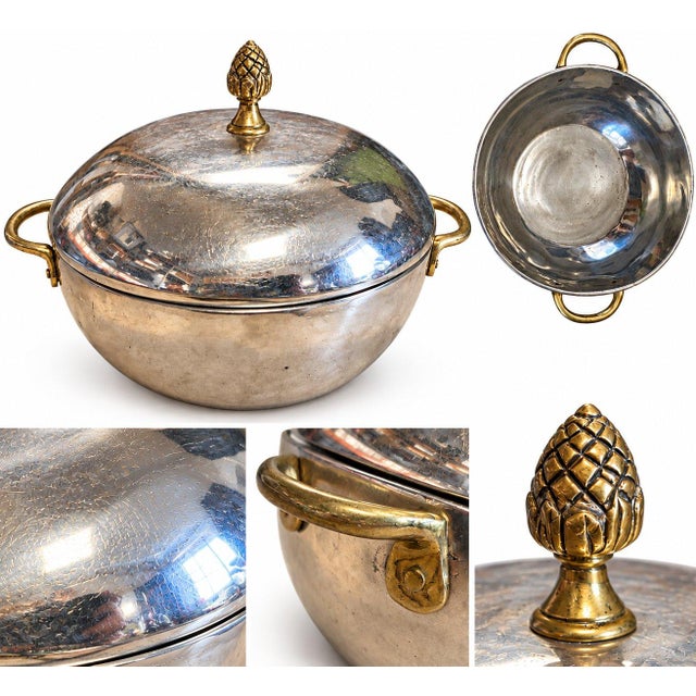 An elegant vintage silver plated casserole vegetable dish featuring a polished silver-tone finish, decorative brass...