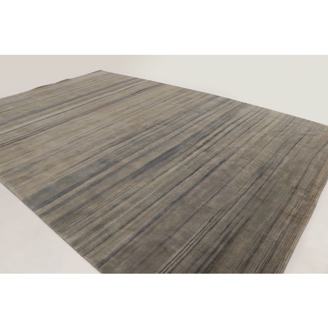This oversized 13x19 contemporary striped rug is handwoven in wool and features layered taupe and charcoal striations that...