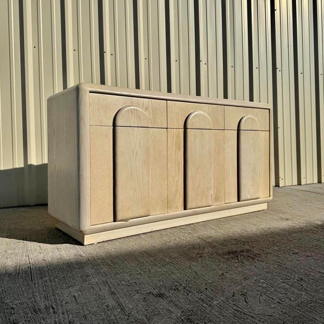 Pickled oak 80s credenza/cabinet featuring carved arched drawer and door fronts. There are three drawers across the top;...