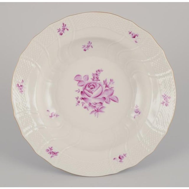 Herend, Hungary. A set of four deep plates. Hand-painted with purple floral motifs. Gold rim. Mid-20th century. Marked....