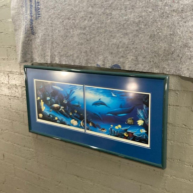 This framed print features a vibrant underwater scene with dolphins, a sea turtle, and colorful tropical fish. The art is...