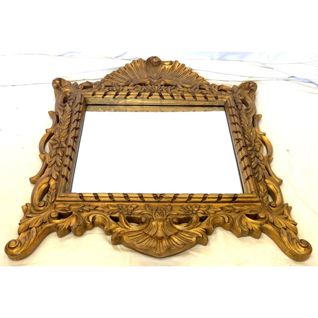 Striking large wall mirror from the late 20th century. The piece is ornately carved in a French Regency style with a high...