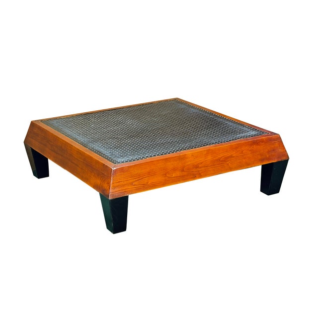 This low-profile square coffee table features a striking blend of rustic textures and clean, architectural lines. The...