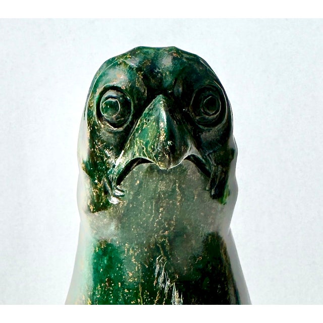 A beautifully carved Chinese hardstone parrot with rich green tones and natural variation, perched on an openwork rock...