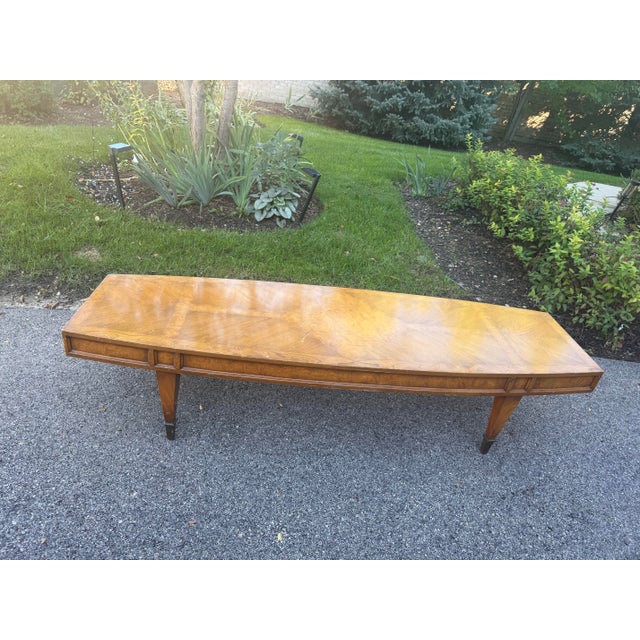 Vintage mid-century modern long burlwood coffee table features a rectangular wood-grain top with tapered legs and dark-...