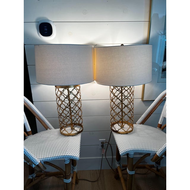Beautiful pair of metallic gold quatrefoil table lamps. The lamp finish is a soft gold metallic and drum shade is in ivory...